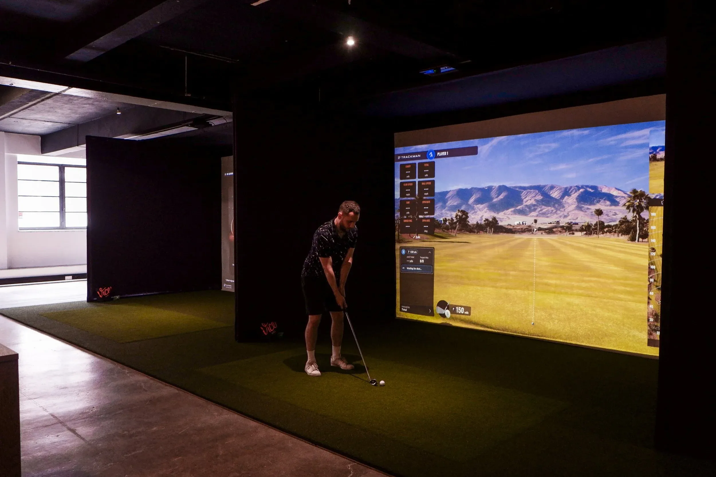 Golfer playing a shot in a Trackman simulator bay at SGC Hampstead Heath